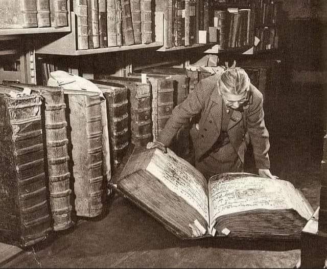 A woman examining giant books in the Prague Castle Archives. Czech Republic, 1940s.